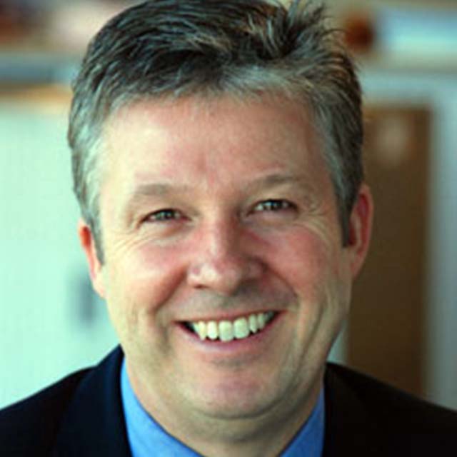 A white man with grey hair smiles