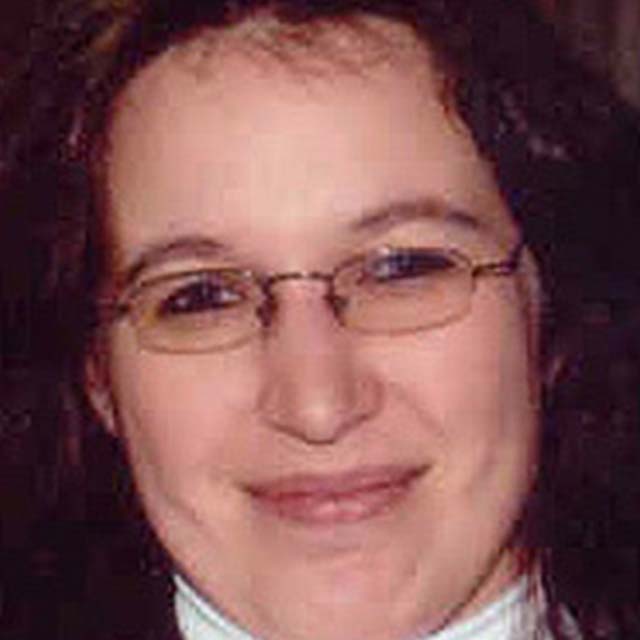 A white woman wearing glasses smiles