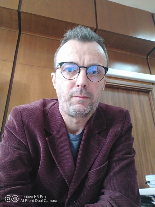 Marian Badea is a White man with short hair who is wearing a purple jacket and glasses.