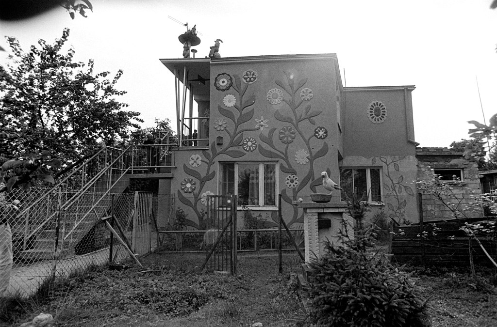 Black and white photo of a two-storey house with beautiful paintings of flowers and plants along the outer wall