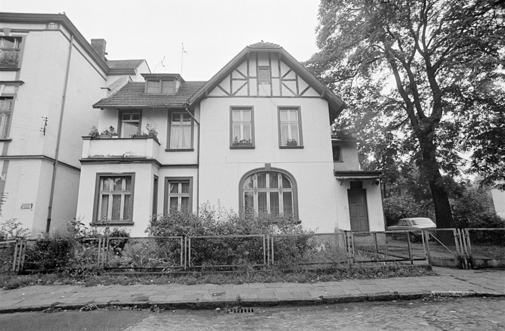 Black and white photo of a two-story house on a suburban street