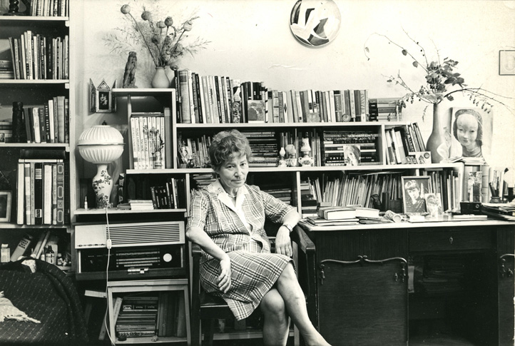 Zofia Rydet is a middle-aged white woman with light wavy hair done up in a beehive. She sits in a large office with a crowded bookcase and various photos and vases with flowers