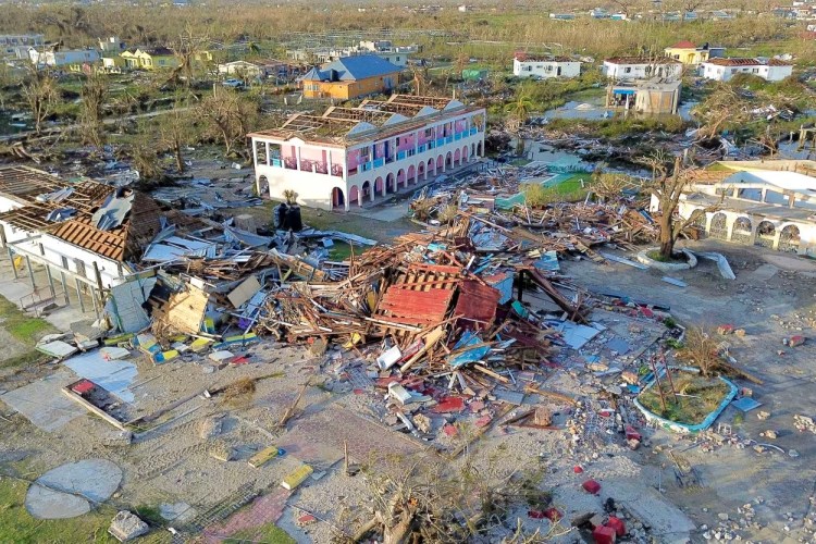 Destroyed houses in a large, now-cleared, field, with a large hotel in the centre missing its roof