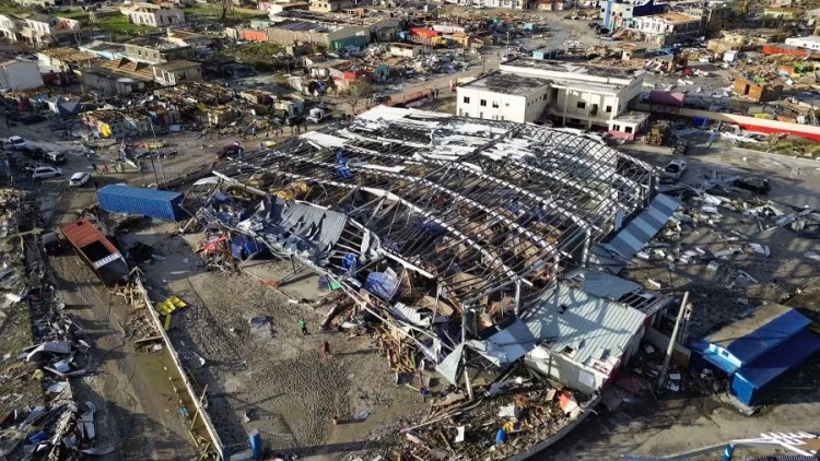 Aerial view of the steel frame of a building fallen to the ground, surrounded by shattered buildings
