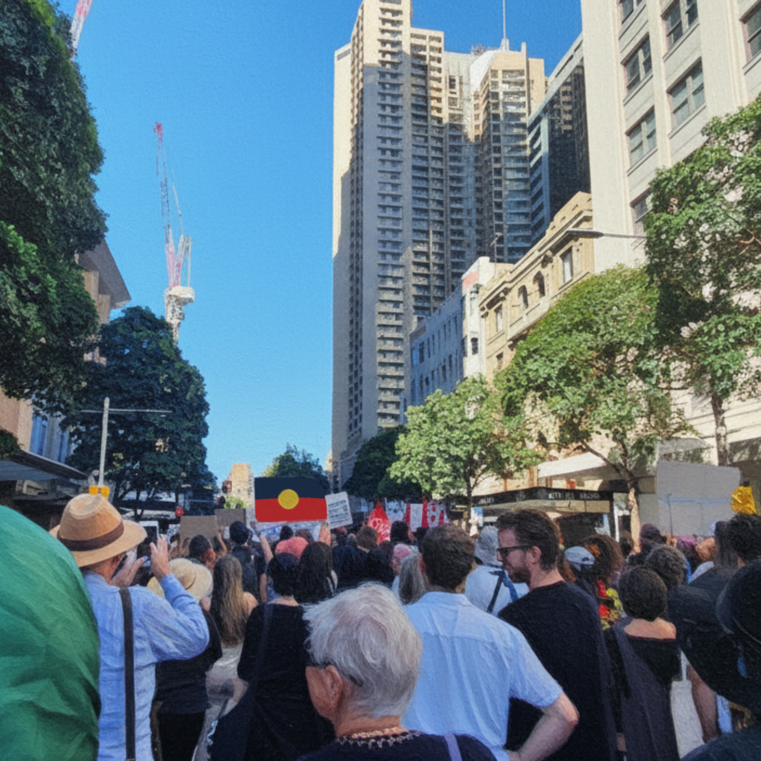 People protesting in Sydney, Australia, holding banners and the Aboriginal flag