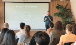 Parker Lemal-Brown is a white man with black hair and a beard. He stands in front of a crowd, with a monitor behind him saying, "Story structure"