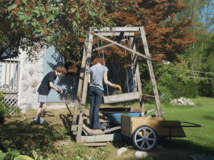 Two young white people work outdoors with shovels and wheelbarrows