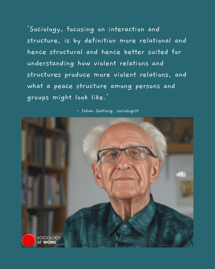 Prof Johan Galtung is an older white man, with white hair balding in the front, and he is wearing glasses. He is wearing a green shirt, with a bookcase in the background
