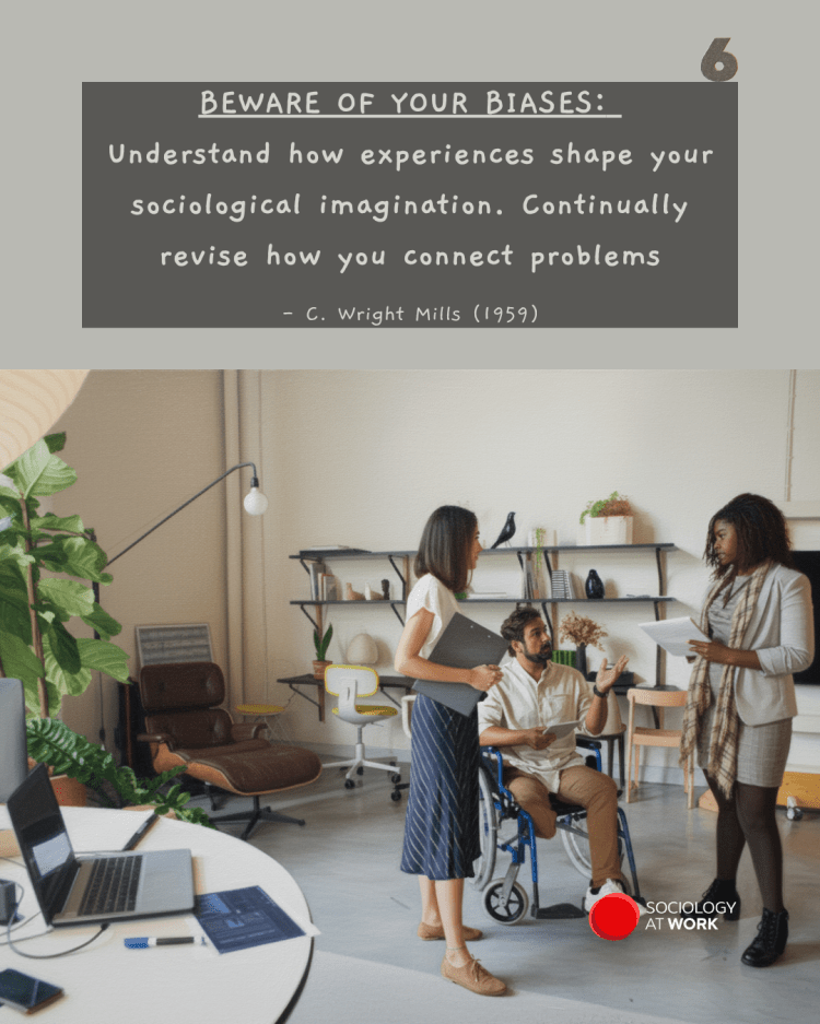 An Asian woman and Black woman stand while speaking with a white male colleague in a wheelchair, in an office